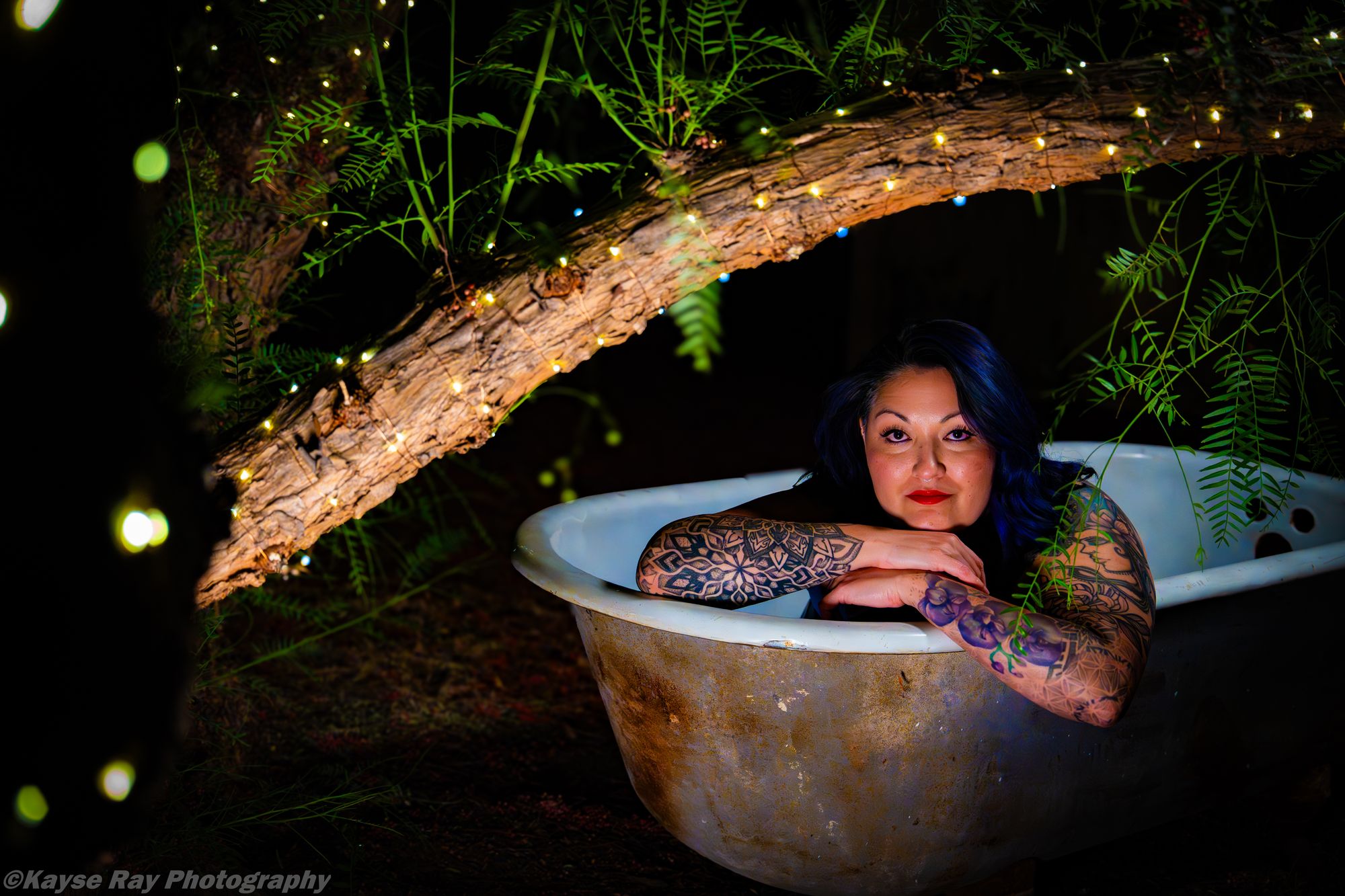 Nighttime portrait in a clawfoot tub lit by warm string lights, by Kayse Ray